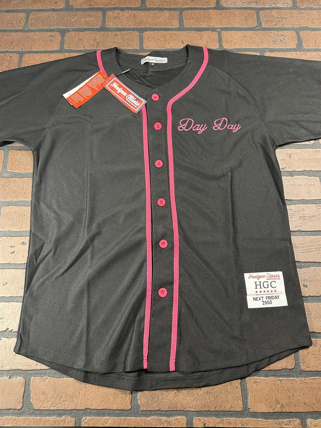 Black baseball jersey with pink accents on a brick background